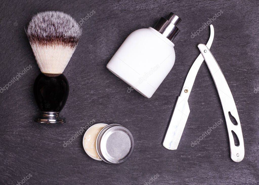 Razor, brush, perfume and balsam on a black background.