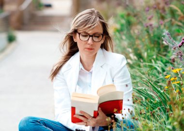 Dışarıda parkta kitap okuyan kadın.