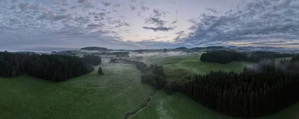 Güneşin doğuşunda bir dronla çekilen sisli ormanın panoramik fotoğrafı