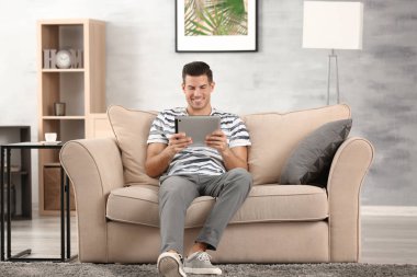 Yakışıklı adam evde koltukta istirahat ederken Tablet PC'yi kullanma