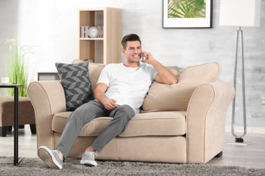 Yakışıklı adam evde koltukta istirahat ederken Cellphone tarafından konuşma