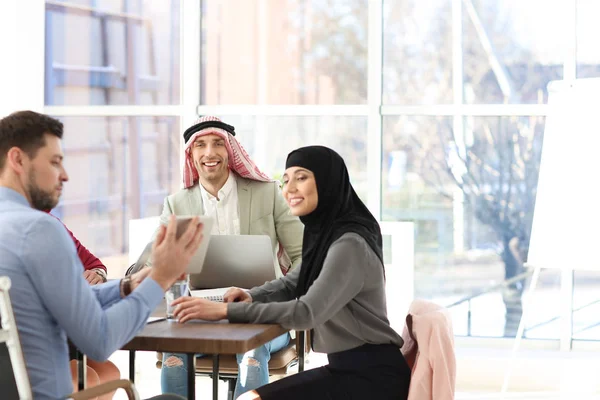 Office employees and Muslim coworkers having business meeting in office