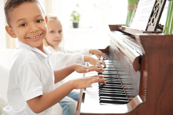African-American boy with little girl playing piano indoors — Stock Photo, Image