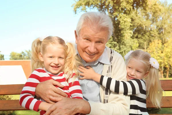 Пожилой человек с внучками в парке — стоковое фото