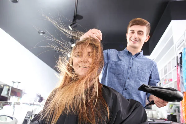 Professional stylist blow drying woman's hair in salon — Stock Photo, Image