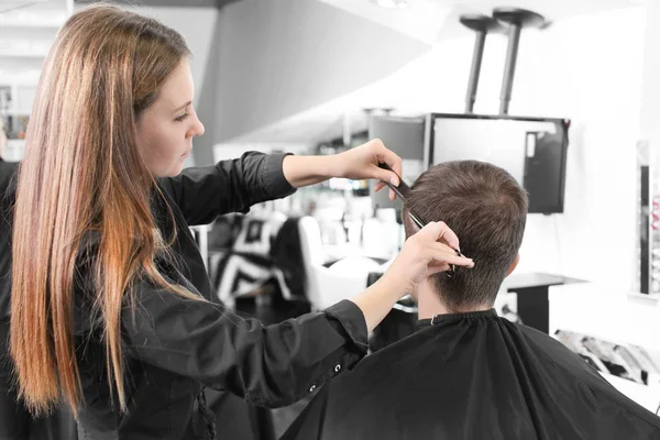 Женщина парикмахер стрижет волосы клиента в салоне — стоковое фото
