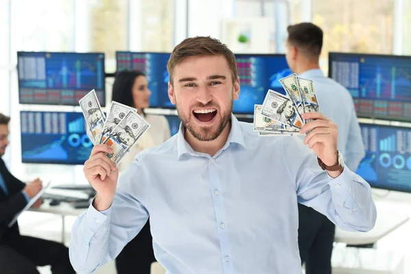 Zadowolony mężczyzna inwestora giełdowego z banknotów dolarowych w biurze — Zdjęcie stockowe