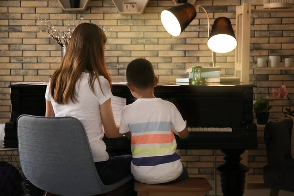 Афроамериканец с учителем, который учится играть на пианино в помещении — стоковое фото