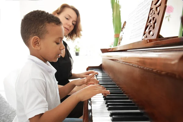 Menino com professor aprendendo a tocar piano — Fotografia de Stock