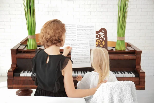 Niña con maestra aprendiendo a tocar el piano en el interior — Foto de Stock