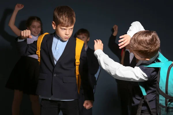 Kleiner Junge schikaniert Mitschüler auf dunklem Hintergrund — Stockfoto