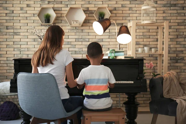 Afro-Amerikaanse jongen met de leraar leren piano spelen binnenshuis — Stockfoto