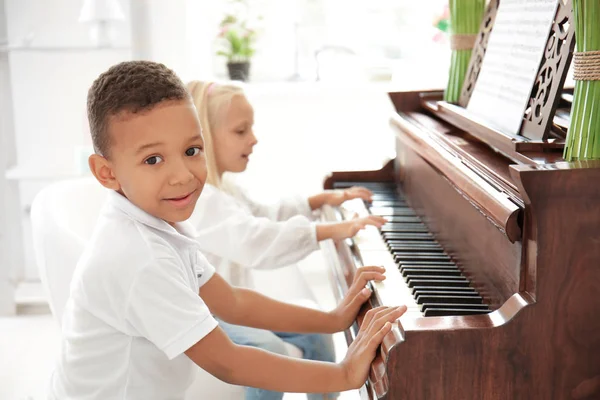 African-American boy with little girl playing piano indoors — Stock Photo, Image