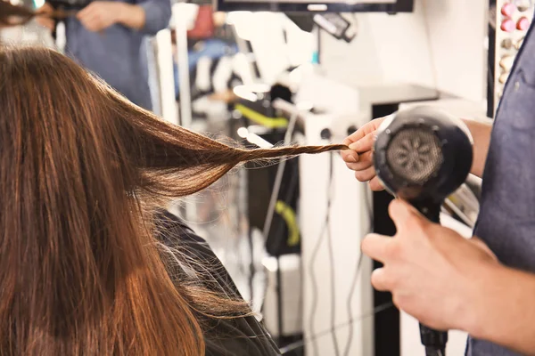 Профессиональный стилист вытирает женские волосы в салоне, крупным планом — стоковое фото
