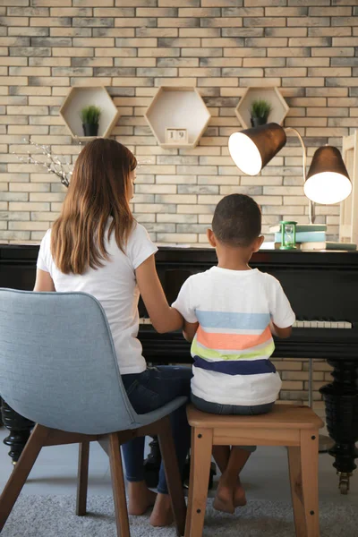 Афроамериканец с учителем, который учится играть на пианино в помещении — стоковое фото