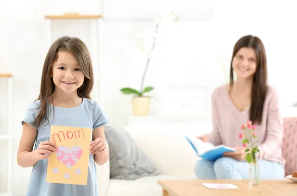 Liten flicka med present till hennes mamma på mors dag inomhus — Stockfoto