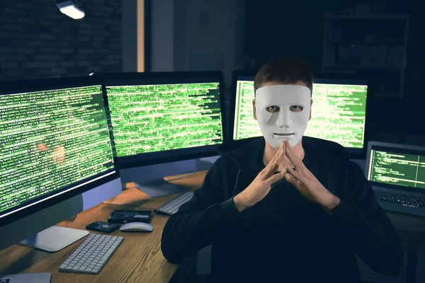 Хакер в маске с компьютерами — стоковое фото