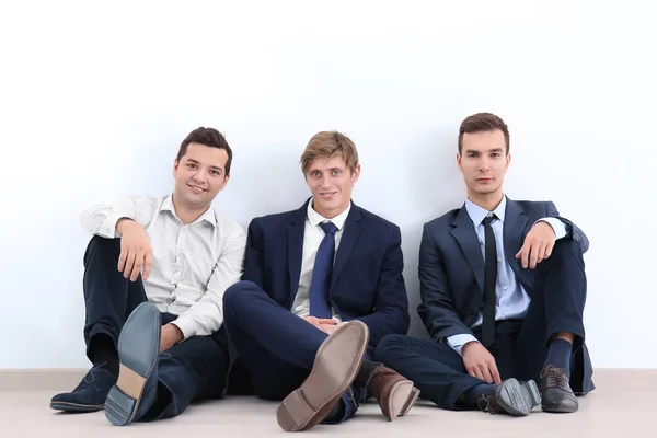 Uomini seduti insieme vicino al muro bianco. Concetto di unità — Foto Stock