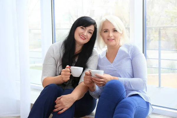 Aantrekkelijke rijpe vrouwen drinken koffie — Stockfoto