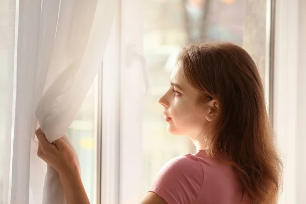 Mujer joven mirando por la ventana interior — Foto de Stock