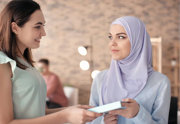 Estudante feminina com seu colega muçulmano na biblioteca — Fotografia de Stock