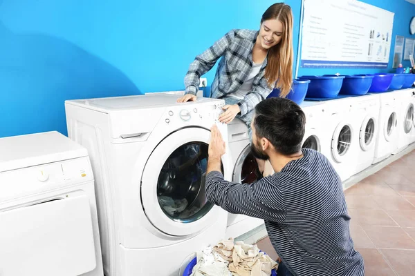 Jovem casal fazendo lavanderia na lavanderia — Fotografia de Stock