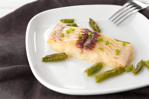 Tallrik med välsmakande fisk och gröna bönor på bord — Stockfoto