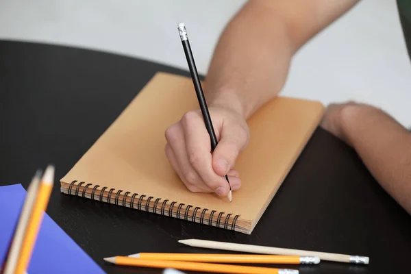 Male student doing homework at table, closeup — Stock Photo, Image