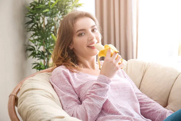 Jeune femme mangeant de la banane à la maison — Photo