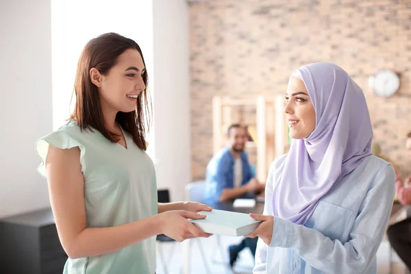 Female student with her Muslim classmate in library — Stock Photo, Image