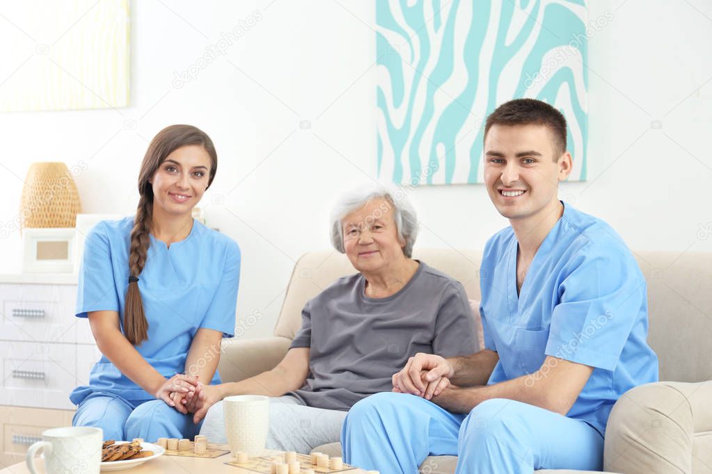 Senior woman with young caregivers indoors