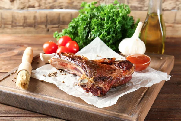 Board with delicious grilled ribs on wooden table — Stock Photo, Image