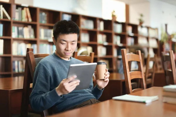 Studente asiatico con tablet che studia in biblioteca — Foto Stock