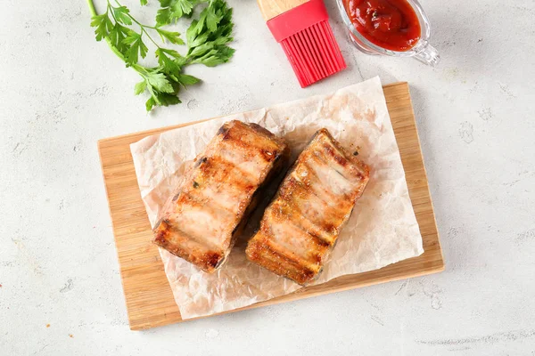 Wooden board with delicious grilled ribs on table — Stock Photo, Image