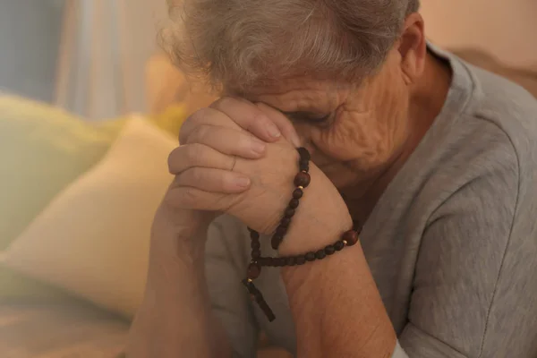 Religiöse ältere Frau betet mit Rosenkranz Perlen, Nahaufnahme — Stockfoto