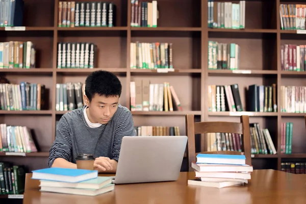 Estudiante asiático con portátil estudiando en la biblioteca — Foto de Stock