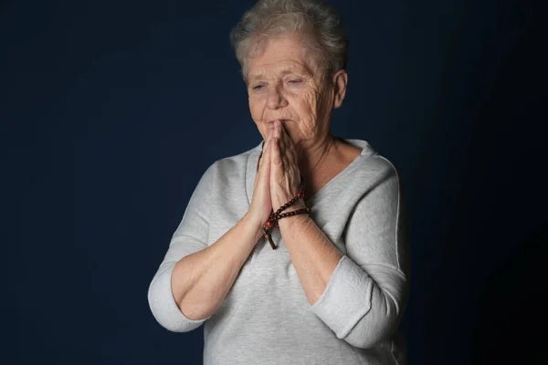 Religious elderly woman praying on dark background — Stock Photo, Image