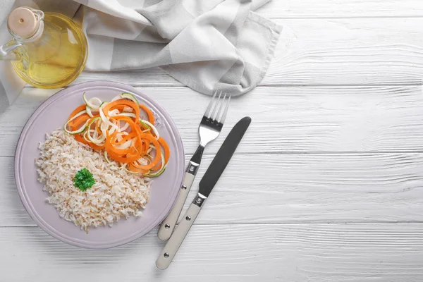 Plato con sabroso arroz integral y verduras en la mesa —  Fotos de Stock