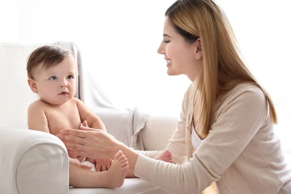 Mulher aplicando creme corporal em seu bebê dentro de casa — Fotografia de Stock