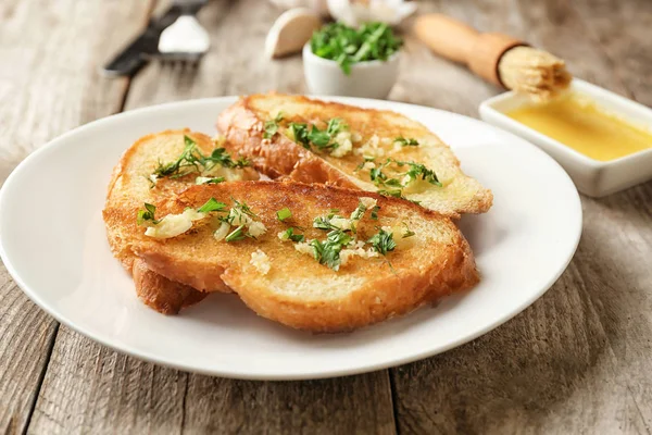 Piatto con delizioso pane all'aglio fatto in casa sul tavolo — Foto Stock