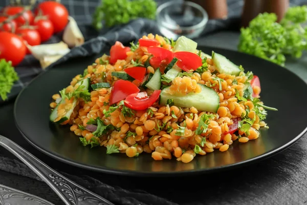 Plate with delicious lentils salad on kitchen table