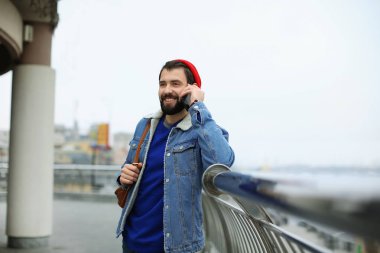 Cep telefonu açık havada üzerinde konuşurken yakışıklı trendy hipster