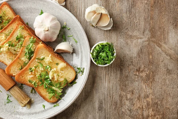 Plate with delicious homemade garlic bread on table