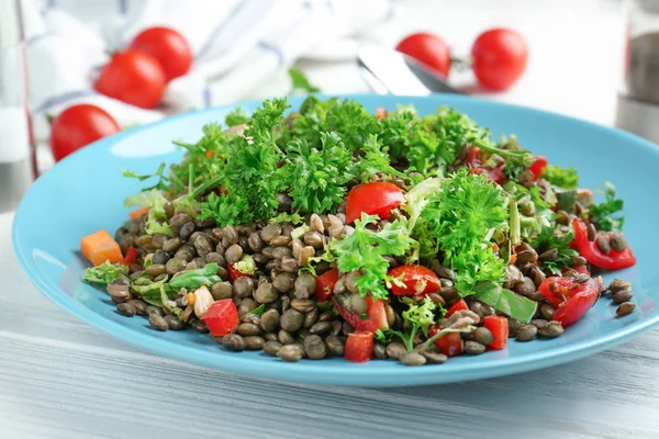 Plate with delicious lentils salad on wooden table — Stock Photo, Image