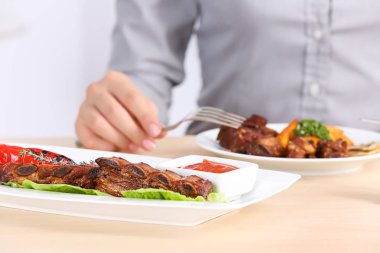 Lezzetli ızgara kaburga ve arka plan üzerinde bulanık kadın ile plaka