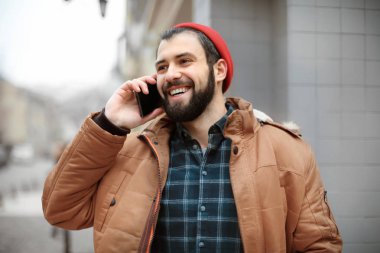 Cep telefonu açık havada üzerinde konuşurken yakışıklı trendy hipster