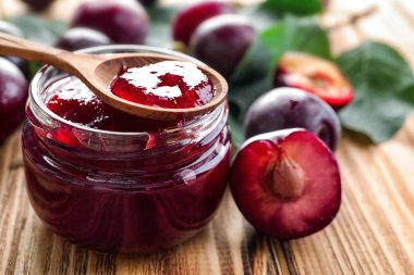 Küçük cam kavanoz ve lezzetli ev yapımı Erik kaşıkla ahşap arka plan üzerinde reçel