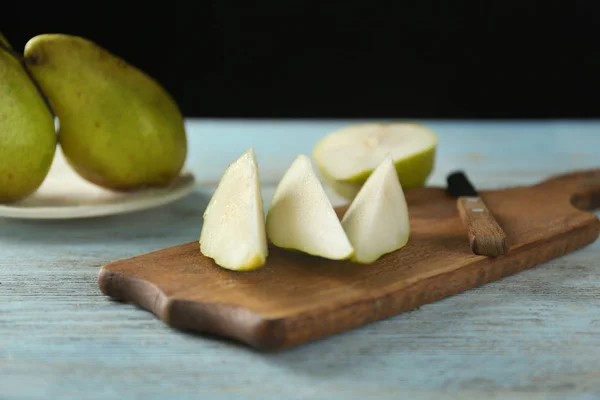 Wooden board with delicious cut pear on table