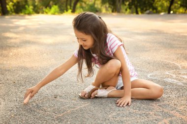 Sevimli küçük kız asfalt üzerinde açık havada tebeşir ile çizim