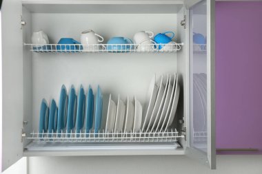 Set of white and blue tableware on drying rack in kitchen clipart